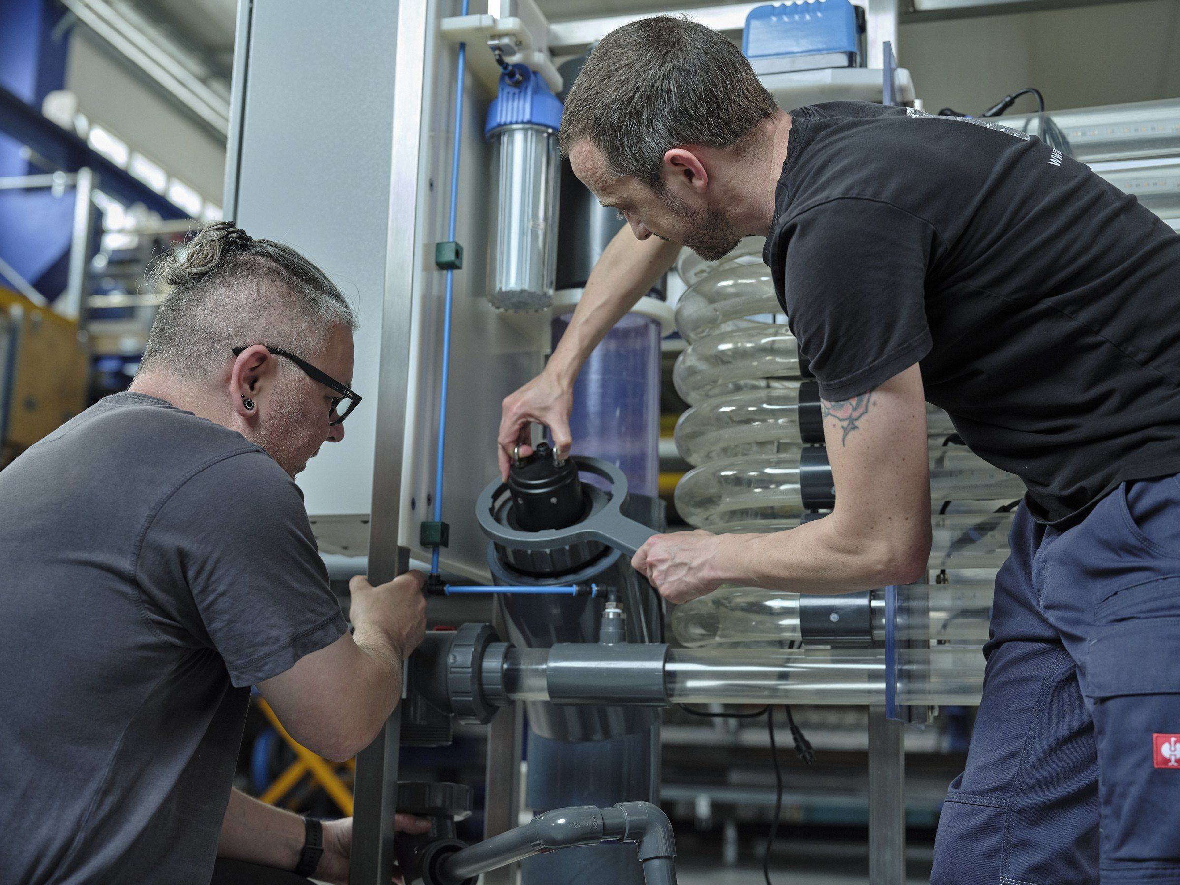 Two fitters assembling a PACT photobioreactor